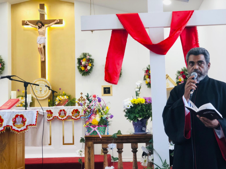 Church interior with crucifix and priest speaking at podium during service