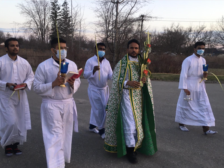 Clergy members in white and green vestments during outdoor religious procession